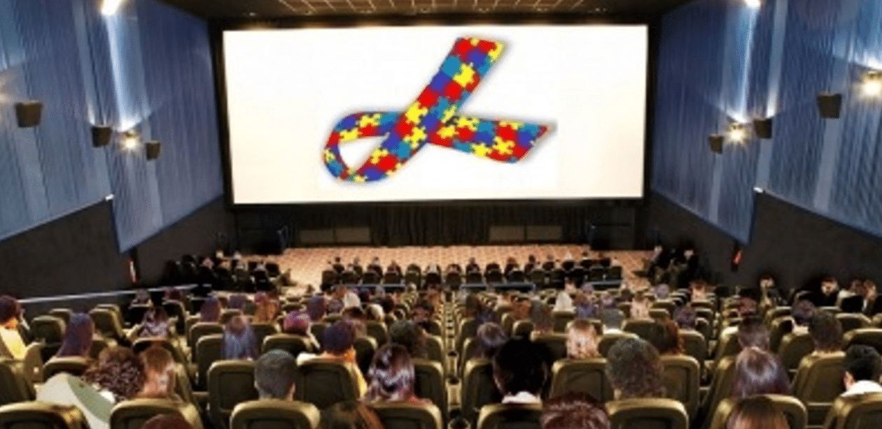 Sessão especial para autistas em cinema com público e símbolo do autismo na tela, promovendo inclusão e acessibilidade.
