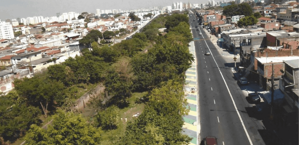 Vista aérea do Parque Linear de Tiquatira com vegetação densa na Zona Leste de São Paulo, ao lado de avenida urbana.