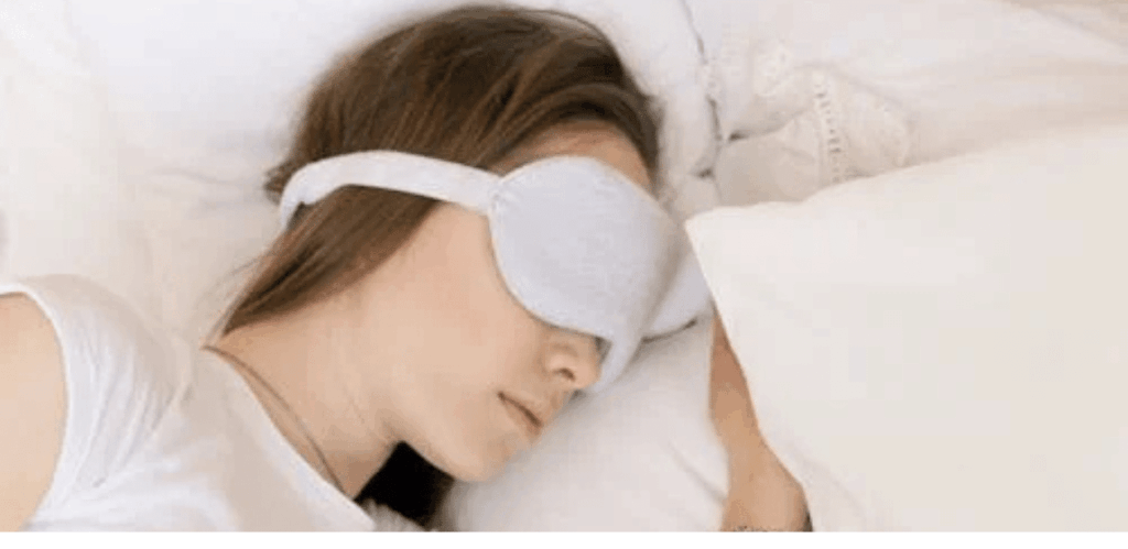 Mulher dormindo com máscara de olhos, representando a busca por qualidade do sono para manter a saúde da tireoide em equilíbrio.