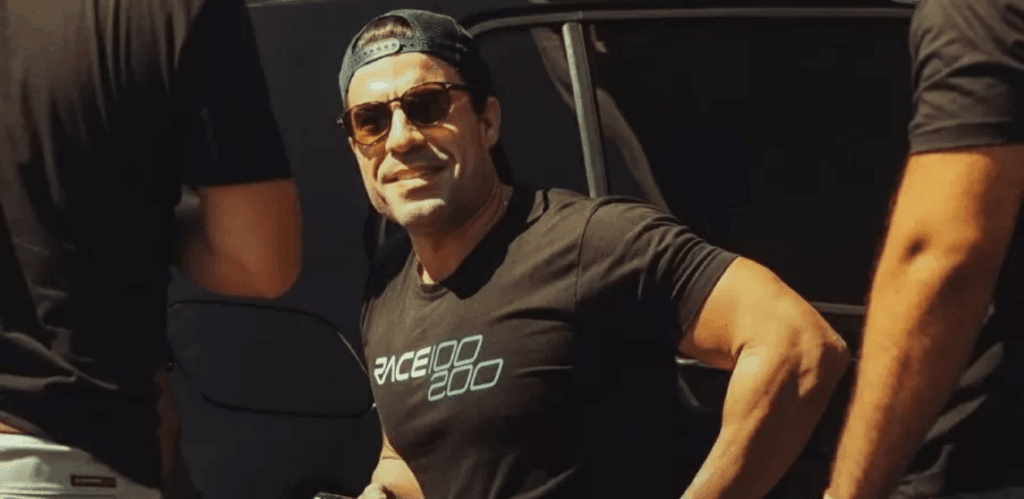 Influenciador Matheus Dressler usando camiseta do Race 100-200, em pé próximo a um carro, após voltar a dirigir com carro adaptado.