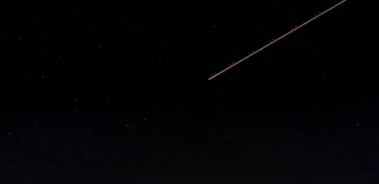 Céu noturno estrelado com rastro luminoso de meteoro cruzando a atmosfera durante uma chuva de meteoros