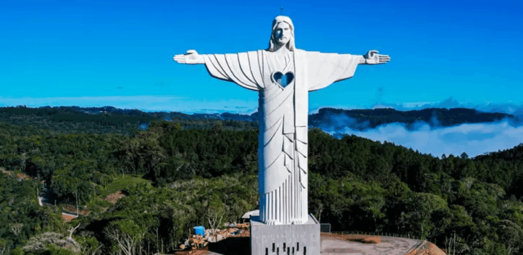 Vista frontal do Cristo Protetor de Encantado com os braços abertos sobre a paisagem do Rio Grande do Sul