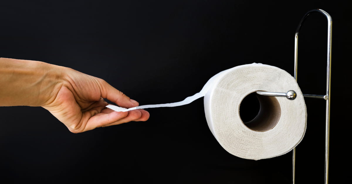Pessoa puxando papel higiênico corretamente pendurado com a folha voltada para frente