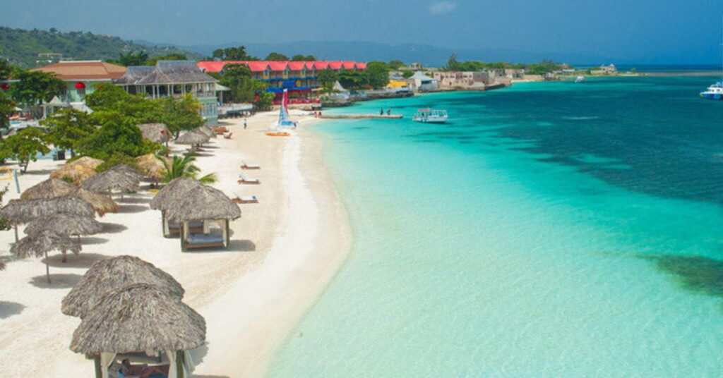 Praia paradisíaca com águas cristalinas e cabanas, símbolo do turismo na Jamaica