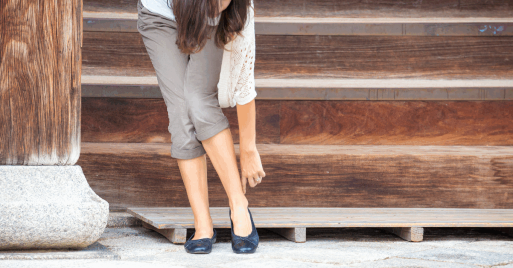Mulher tirando o sapato ao entrar em casa, prática que melhora a saúde e a qualidade do ambiente.
