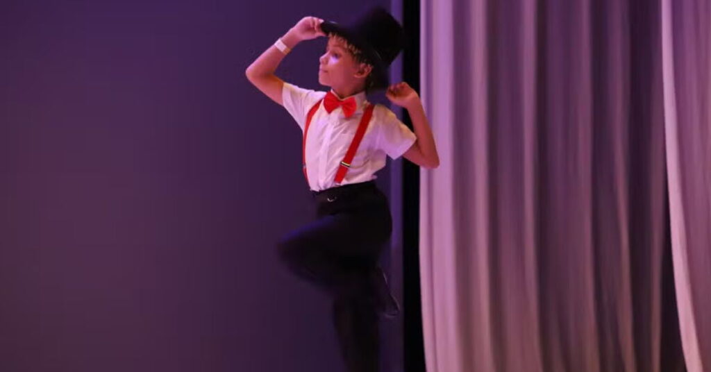Bailarino de 9 anos se apresenta no palco com figurino elegante