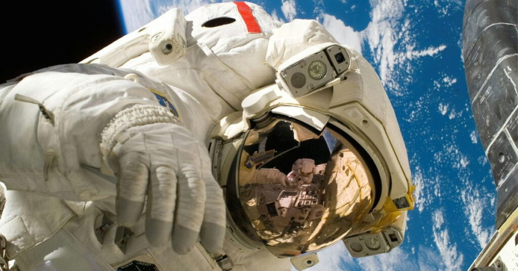 Astronauta em atividade no espaço com a Terra ao fundo