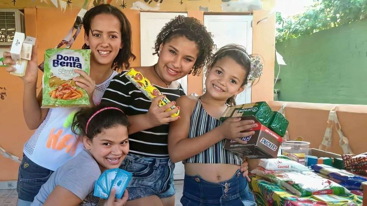 Crianças comemoram recebimento de alimentos e produtos no Eco Mercado, projeto do NEAC que promove inclusão social por meio da troca de recicláveis em Campo Grande (RJ).