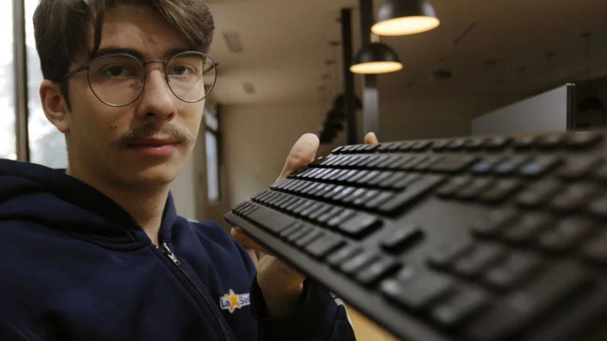 Estudante na olimpíada de IA na China segura teclado com expressão confiante.