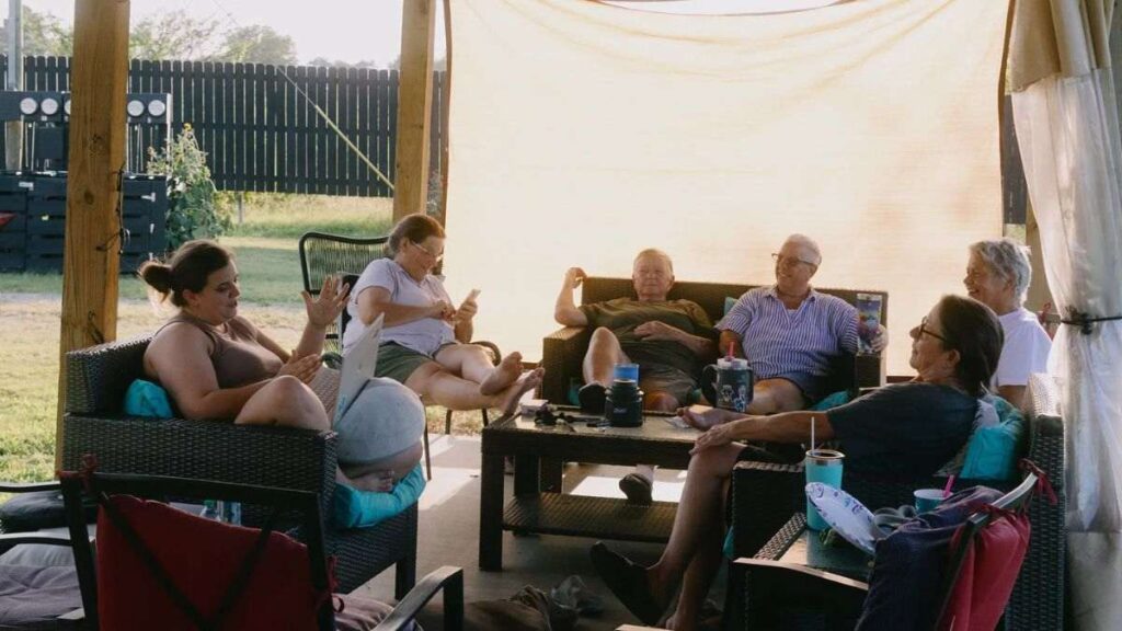comunidade de mulheres aposentadas reunidas em área externa coberta, conversando e relaxando em sofás, representando convivência harmoniosa e envelhecimento ativo