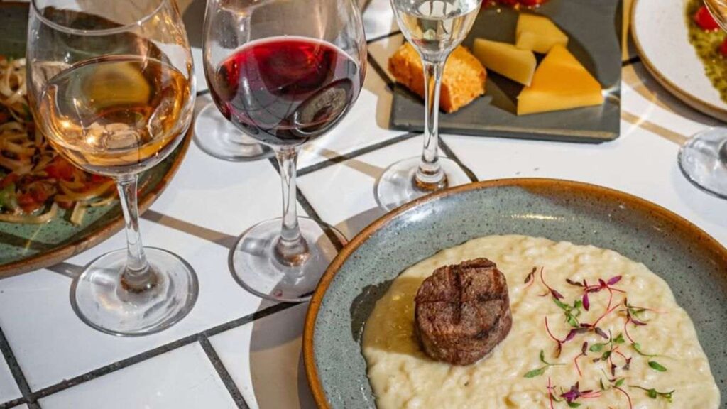 Harmonização à mesa no Bocca Nera Bar, com risoto, queijos, massas e taças de diferentes vinhos em Pinheiros, São Paulo. - Wine bars no Brasil