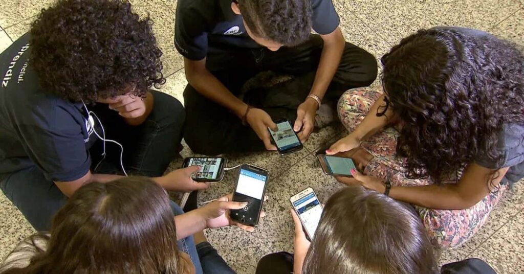 Jovens usando celular em grupo, representando a importância do ECA Digital para a proteção infantil online