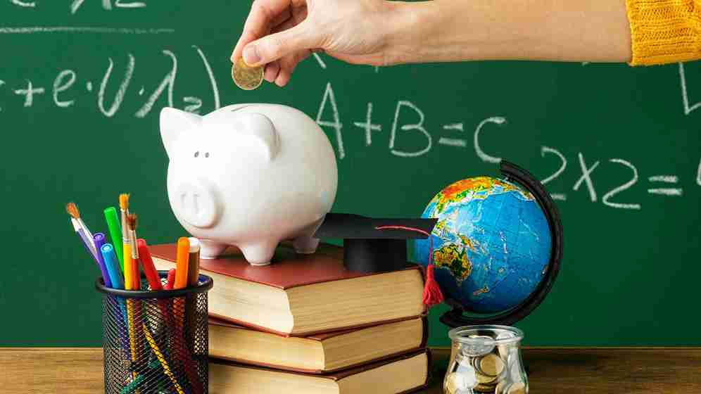 Pessoa colocando moedas no cofrinho com livros e lápis - Olimpíada de educação financeira (OLITEF)