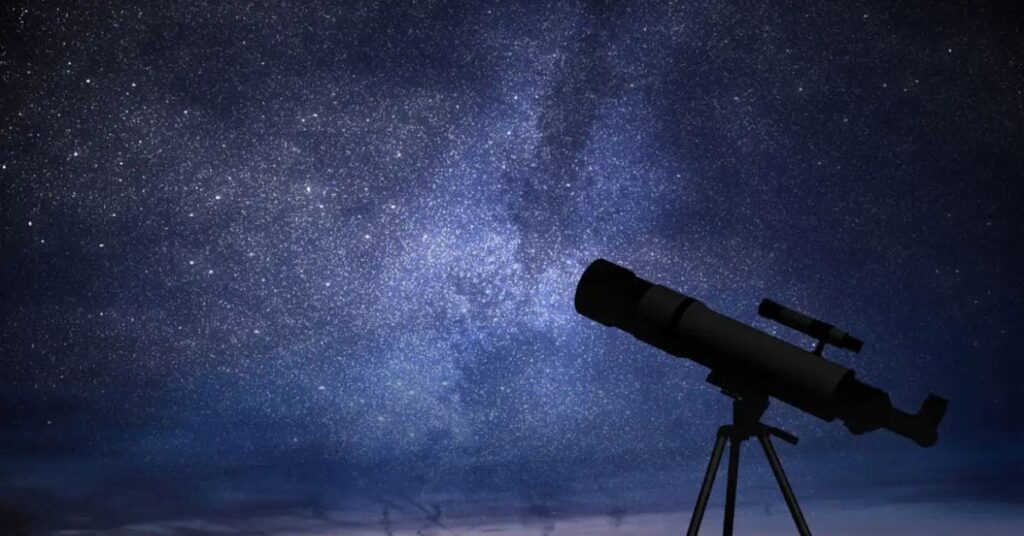 Céu estrelado com telescópio apontado para as estrelas, representando a olimpíada de astronomia.