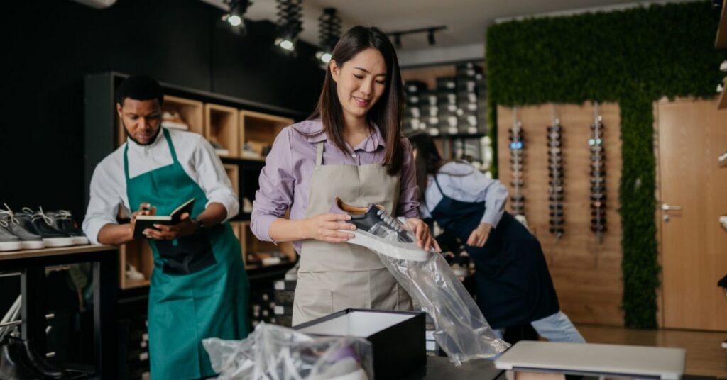 empreendedorismo jovem no Brasil -Jovens empreendedores brasileiros em loja colaborativa, embalando produtos e gerindo negócios com propósito.