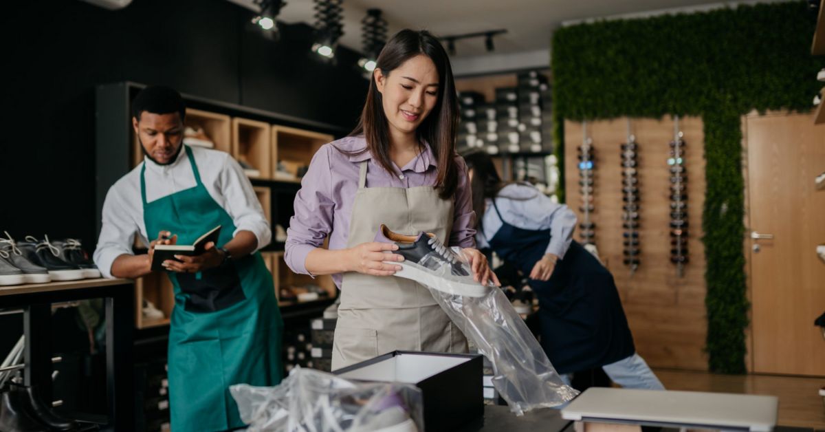 empreendedorismo jovem no Brasil -Jovens empreendedores brasileiros em loja colaborativa, embalando produtos e gerindo negócios com propósito.