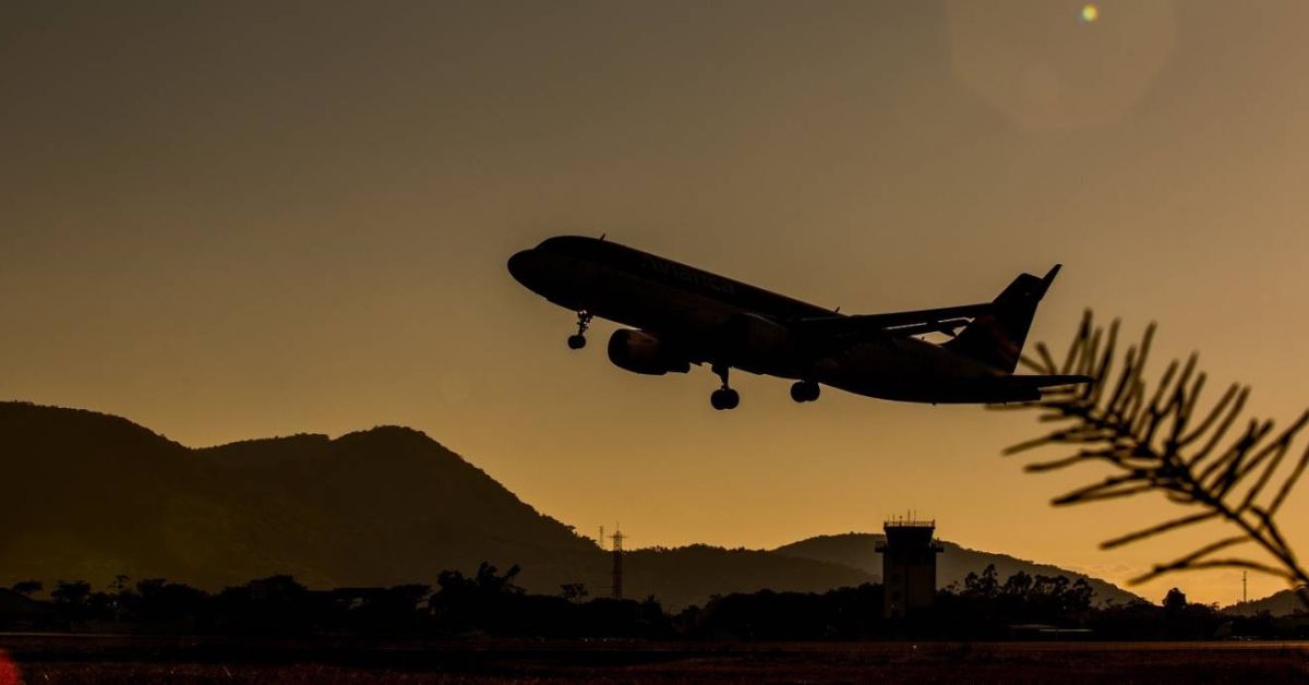 avião decola no Aeroporto Internacional de Florianópolis ao pôr do sol, símbolo do avanço do turismo internacional no Brasil.