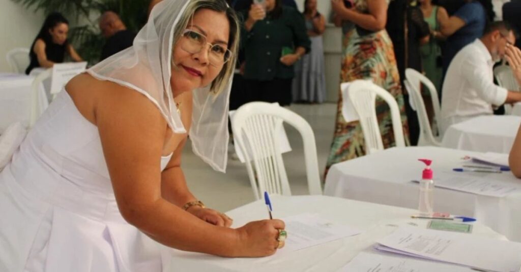 Professora toma posse vestida de noiva assinando documentos em cerimônia de concurso público da educação em Roraima